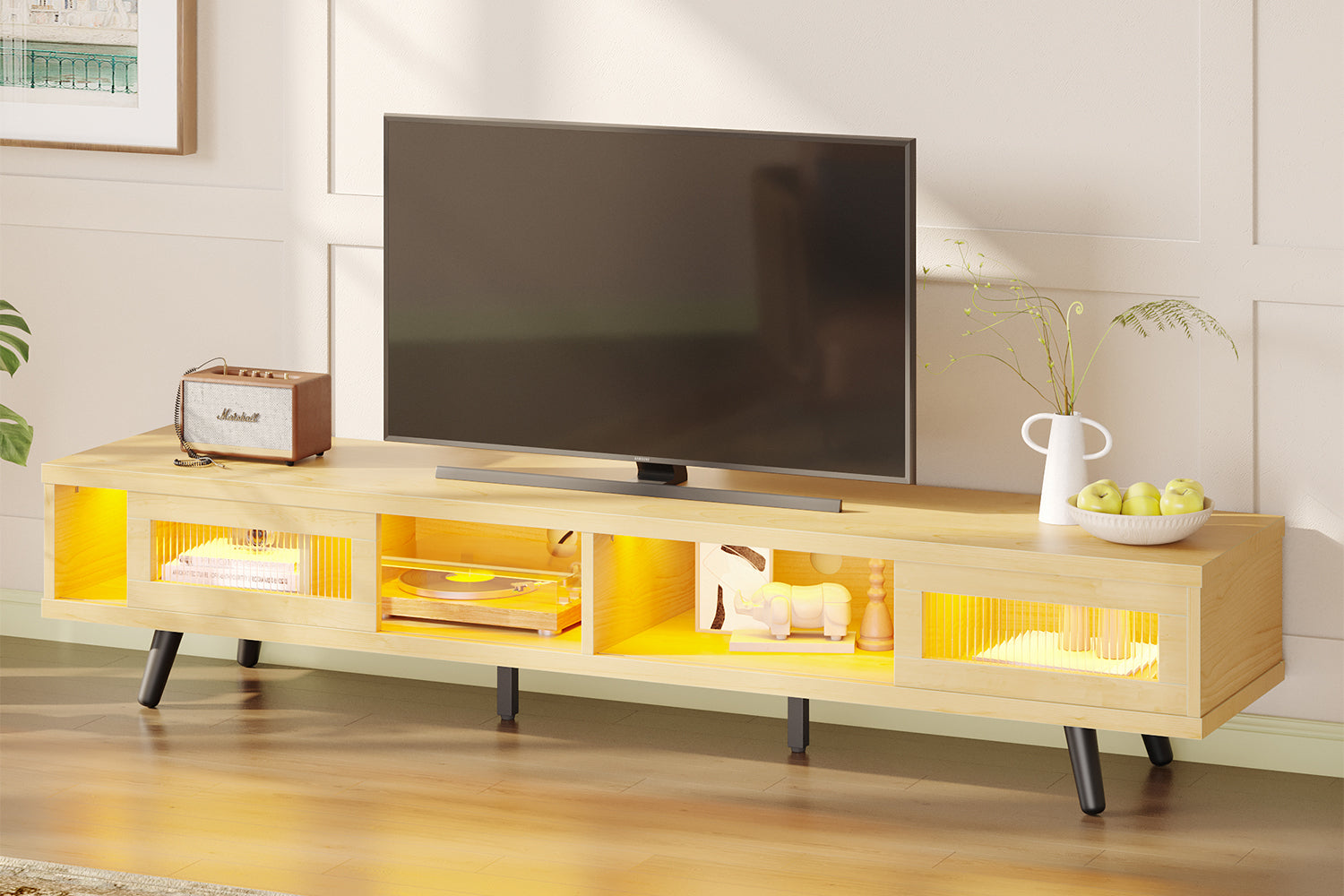 A modern, light wood freestanding TV stand with warm yellow LED backlighting, shown in a cozy living room setting.