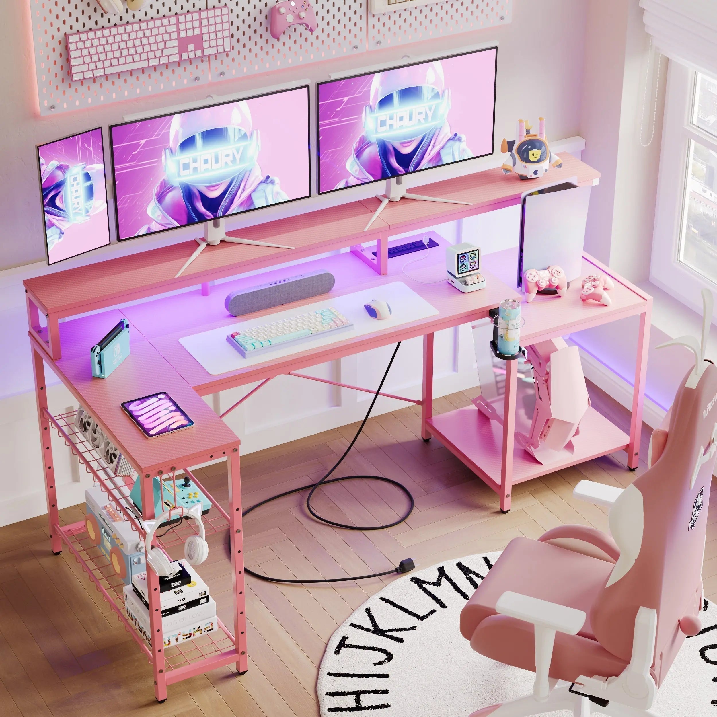 Pink L-shaped gaming desk featuring dual monitors on a riser, a matching ergonomic chair, and organized pegboard shelving.