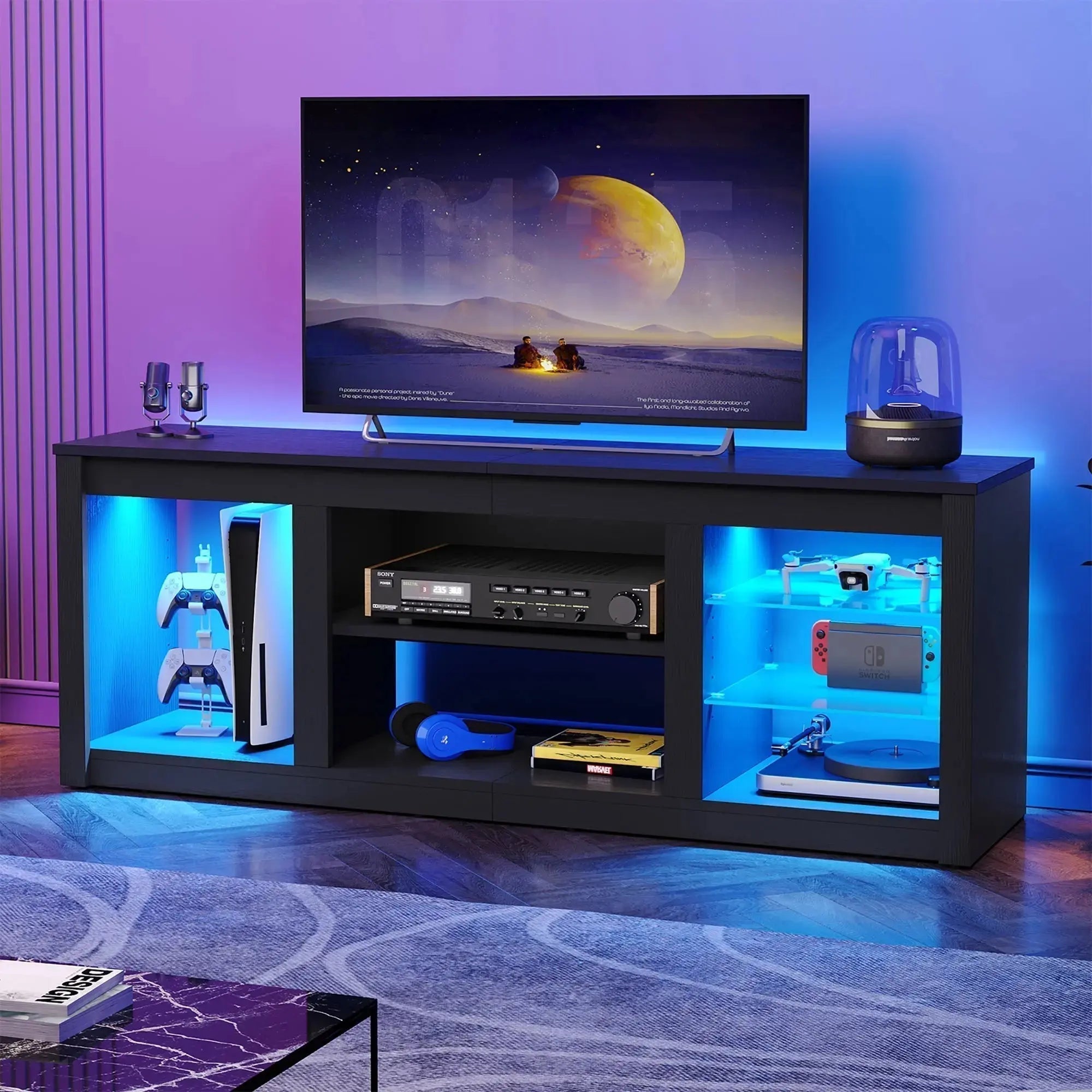 A sleek TV stand with blue LED-lit shelves displaying gaming consoles, headphones, and audio equipment beneath a large flat-screen TV.